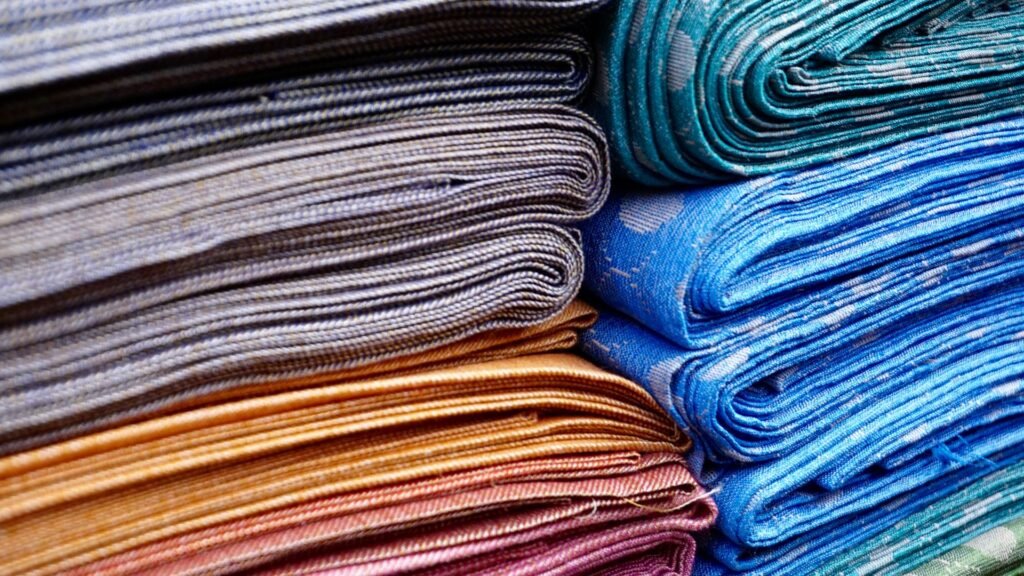 Folded wholesale fabrics in grey, teal, blue and copper tones