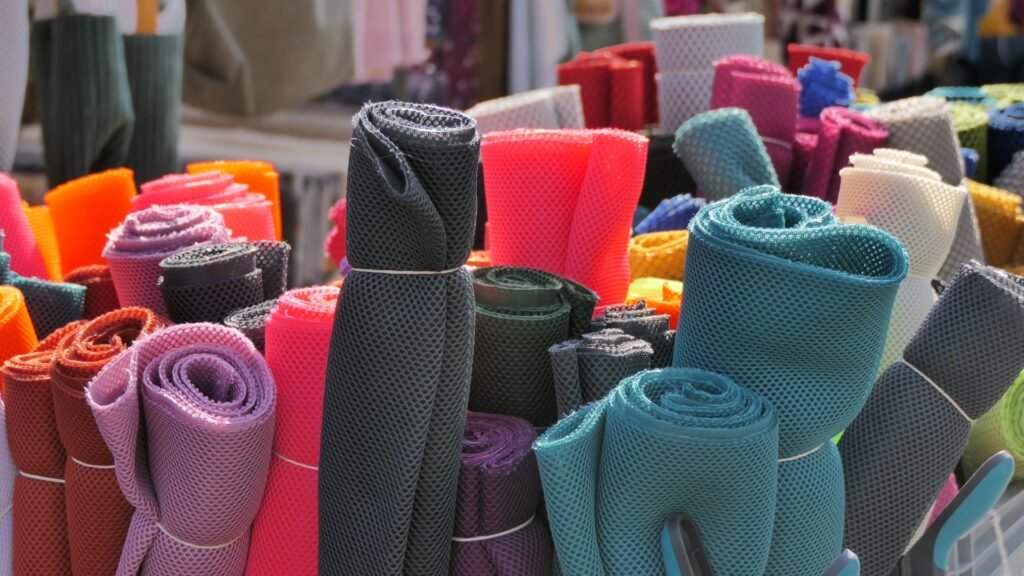 Rolls of colourful knitted mesh fabric in a textile warehouse